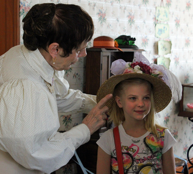 The presenter adjusts a visitor's hat