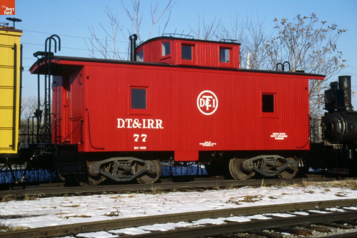 Detroit Toledo & Ironton Railroad Caboose, 1925 Red caboose with text on it sitting on railroad tracks