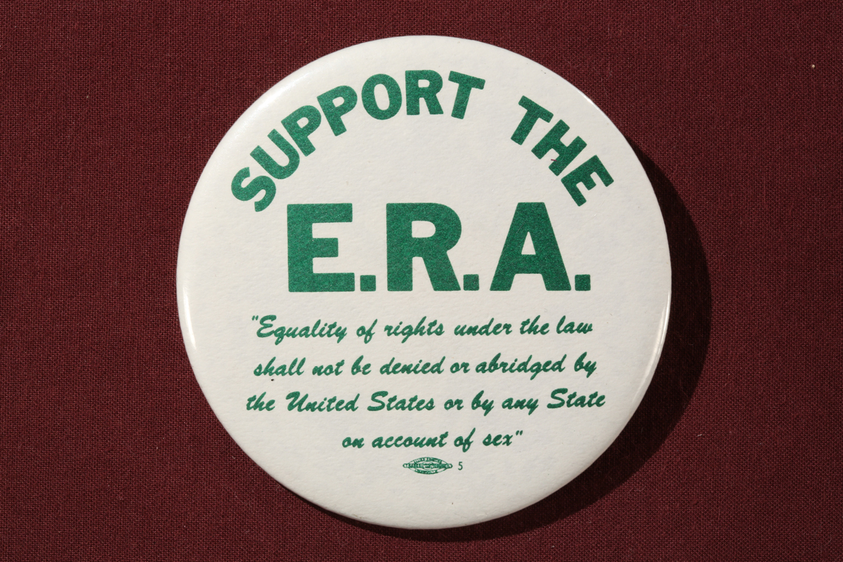 Round white button with green block text reading in part “Support the E.R.A."