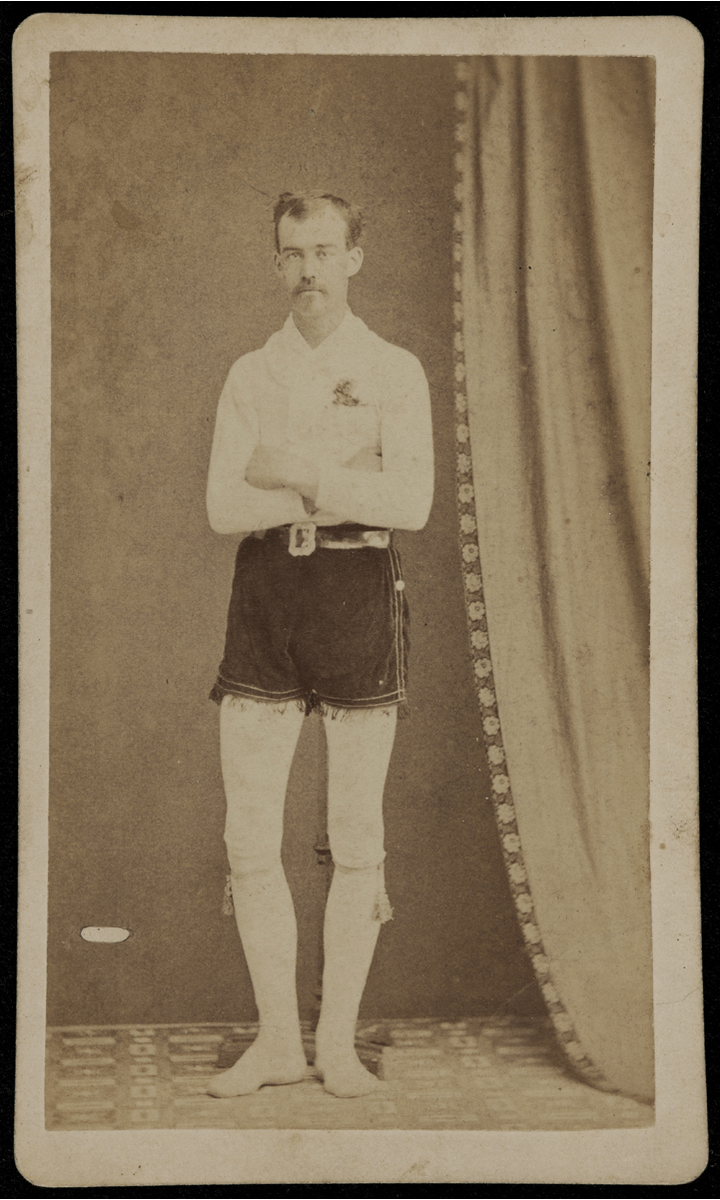 GIF cycling through four black-and-white photos of men standing with arms crossed, wearing white long-sleeved shirt, white tights (?), and dark velvet shorts with fringe