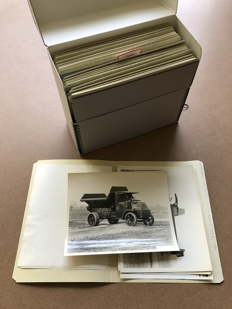 8 x 10 photos in folders in an archival box box standing vertically; folder open in front of it with photo lying on top