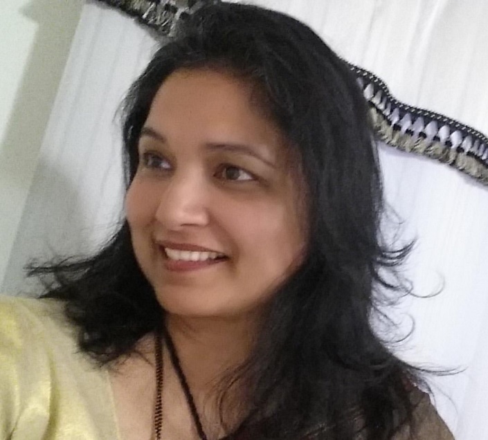 Medium-skinned woman with dark hair in front of white curtain with dark trim