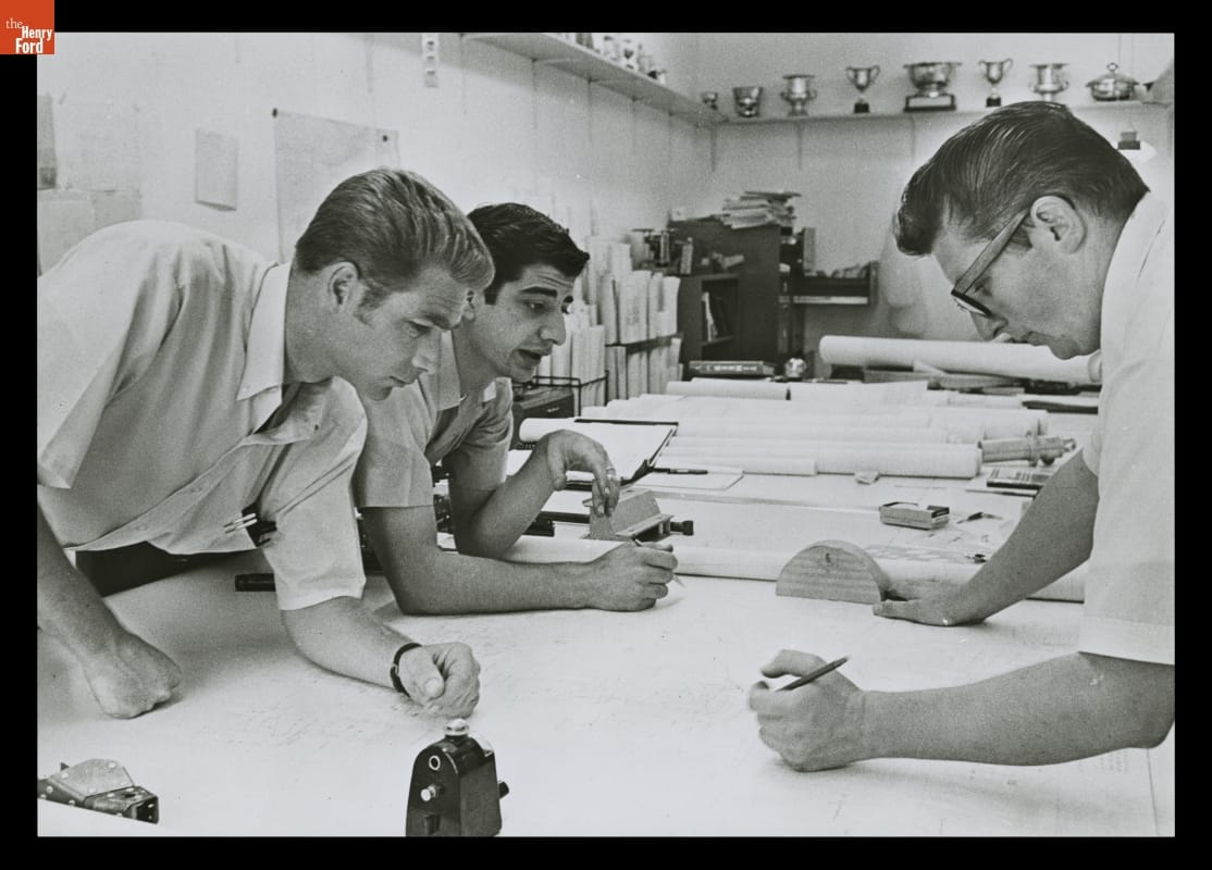Jim Hall and Engineers at Chaparral Cars, Midland Texas, Summer, 1968 Three men lean over a large table filled with drawings and other items