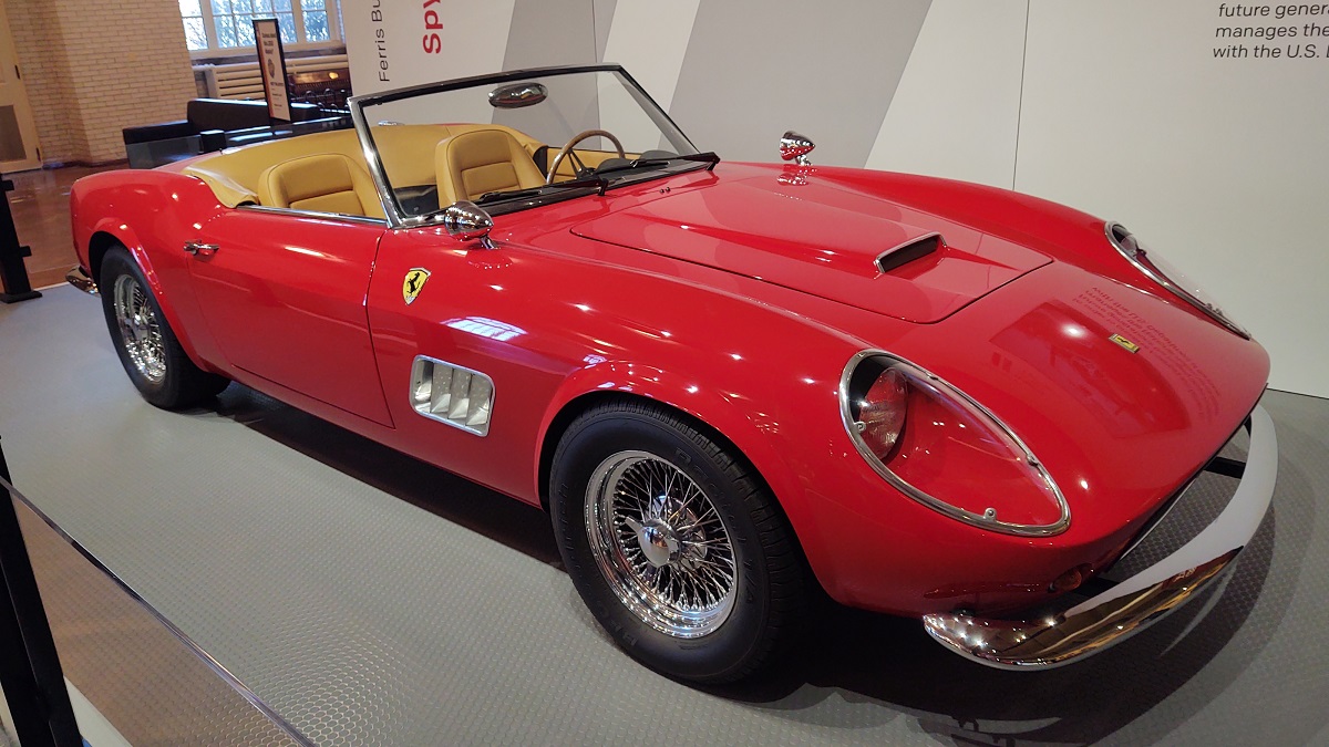 The 1985 Modena Spyder California that played the part of a Ferrari 250 GT California Spyder in the movie Ferris Bueller’s Day Off A sleek red convertible with tan interior and top down is parked in a display indoors