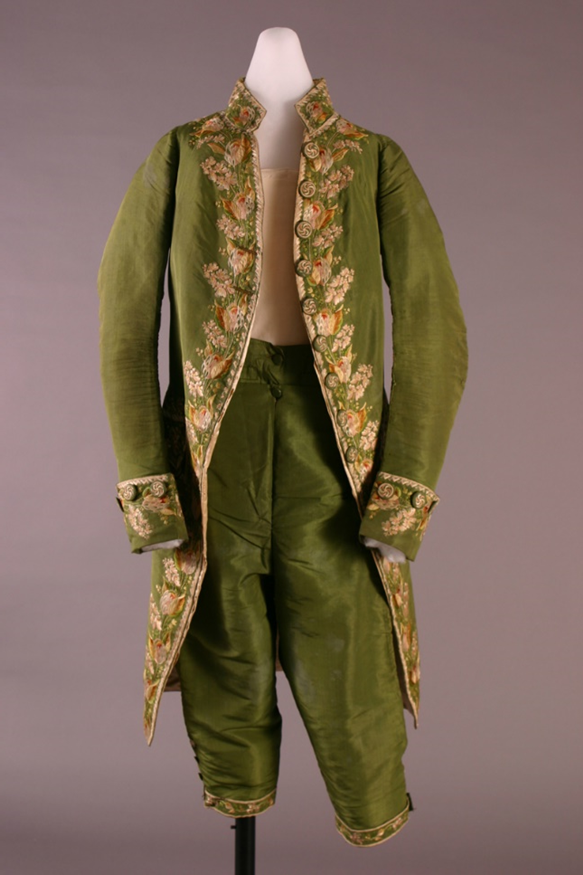 Moss-green man's suit on mannequin; knee-length breeches and long-open coat with embroidery all along front seams and on cuffs