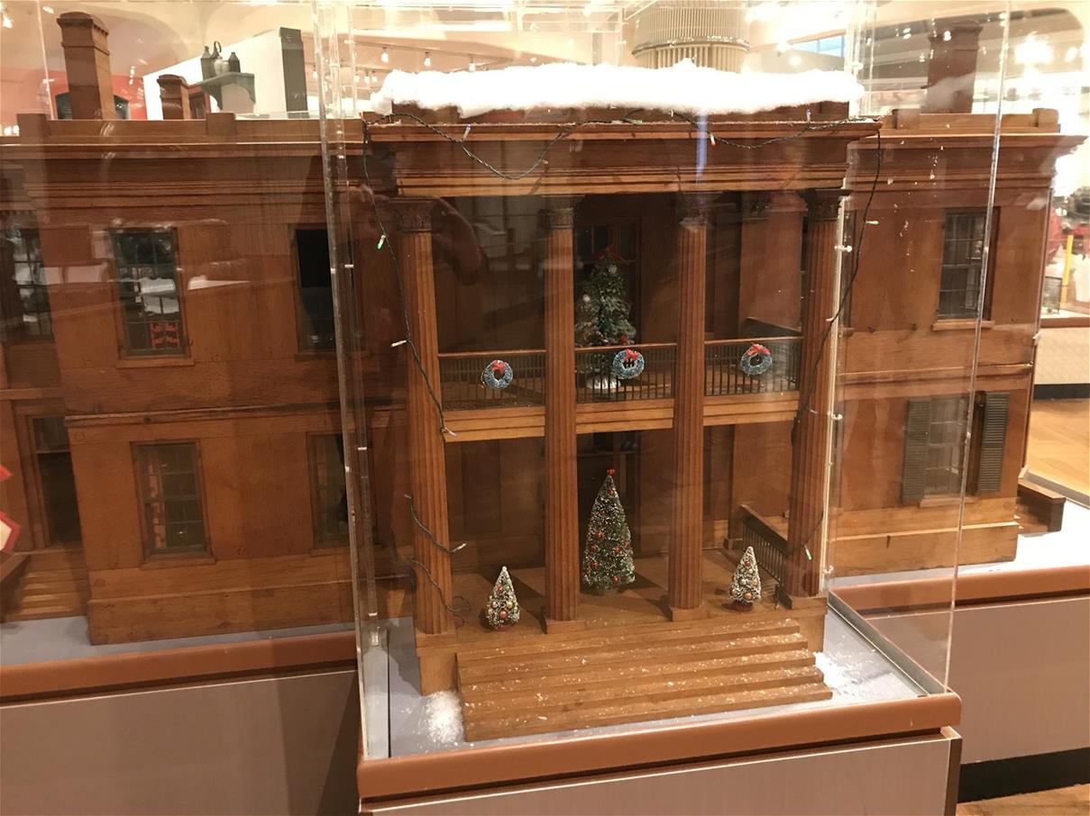 Large model house decorated with tiny Christmas trees and wreaths