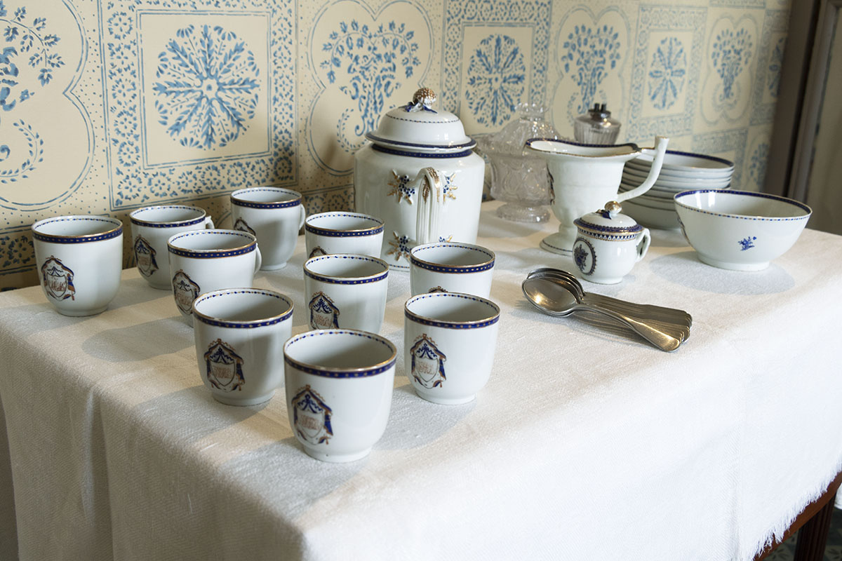Table containing white dishes with blue pattern; wallpapered wall in background