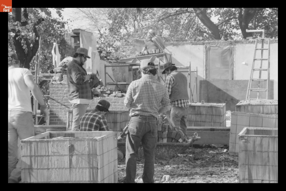 Dismantling the Firestone Farmhouse on its Original Site, November 1983 Black-and-white image of several men working on a construction site