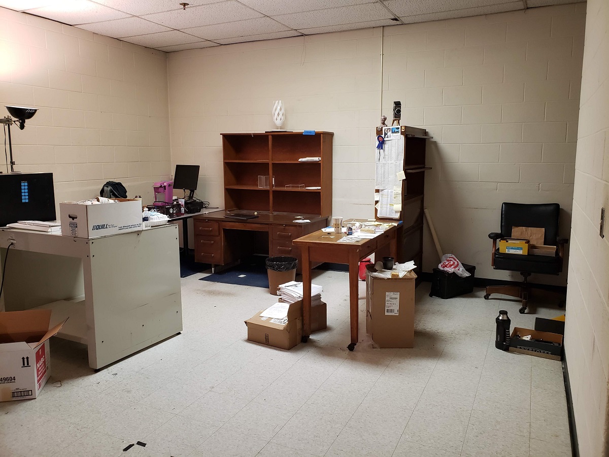 Our old (quite empty) office in the museum’s former Photo Studio Room containing desks, shelves, chair, and boxes