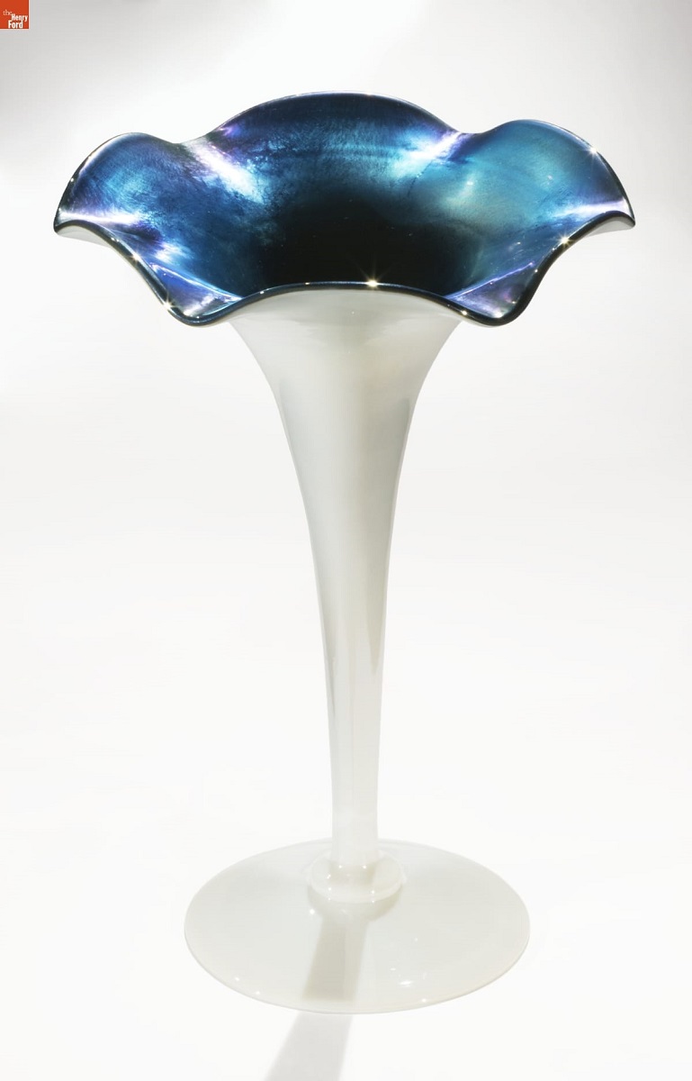 Aurene Vase, circa 1920 White glass vase with stem widening out from narrow at bottom to a crenellated flower shape opening at top; inside is iridescent blue