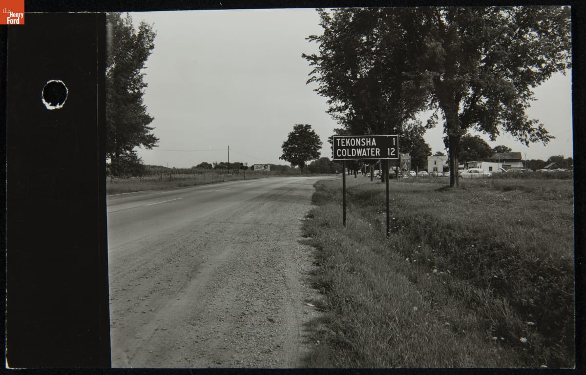 Road Sign near the Original Site of Dr. Howard's Office, Tekonsha, Michigan, August 1959 Road sign next to dirt road running by fields and buildings