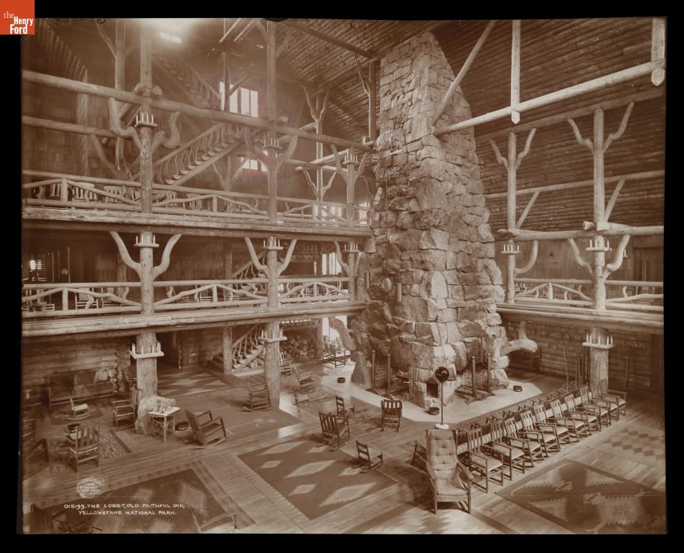 Rustic building lobby with several levels with walkways around the perimeter and a multiple-story stone fireplace