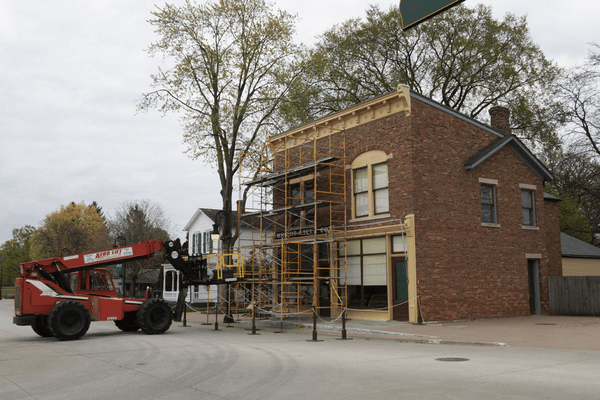 Lifting the C. Webbert Block sign onto the roof of the Wright Cycle Shop GIF cycling through several images of a forklift lifting a sign onto a building roof