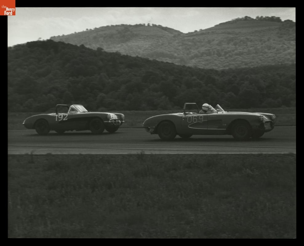 Chevrolet Corvette Race Cars in S.C.C.A. Race, Cumberland, Maryland, May 1959 Two open-top race cars on a road or track with wooded hills in the background