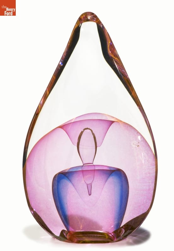 Translucent glass sculpture in teardrop-like shape with clear, pink, and blue glass