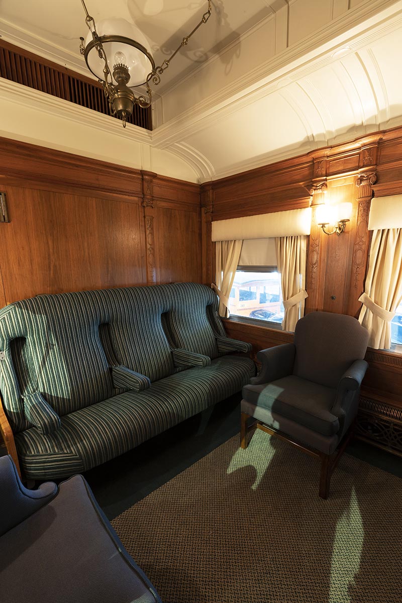 Fair Lane railroad car lounge Interior space with blue upholstered furniture and wood paneling