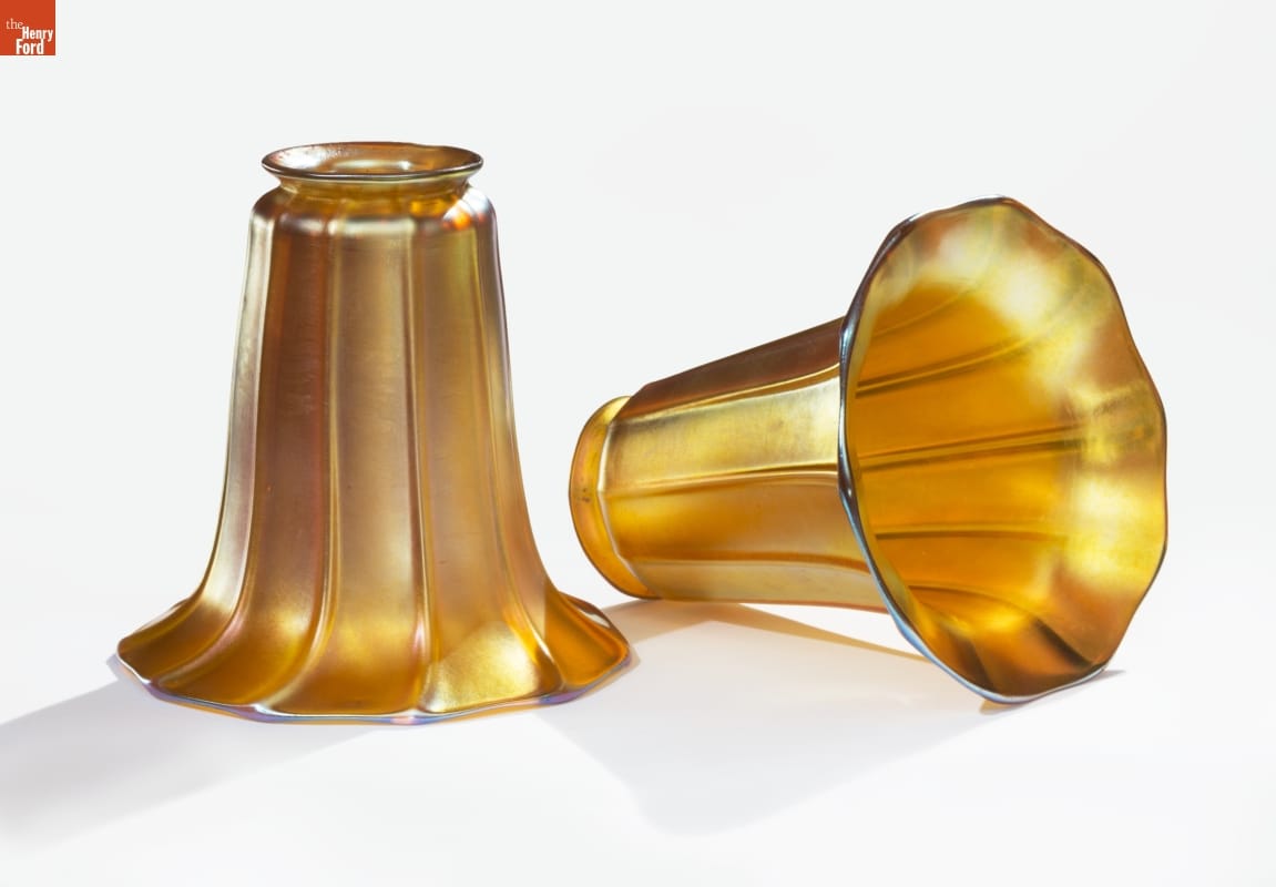 Two trumpet-shaped lampshades in iridescent gold, one laying on side and one upright