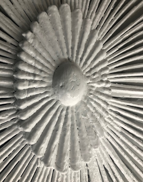 Center of the decorative ellipse from the front pediment of the Noah Webster Home Close-up of architectural element in flower shape with radiating petals/tines coming out from it