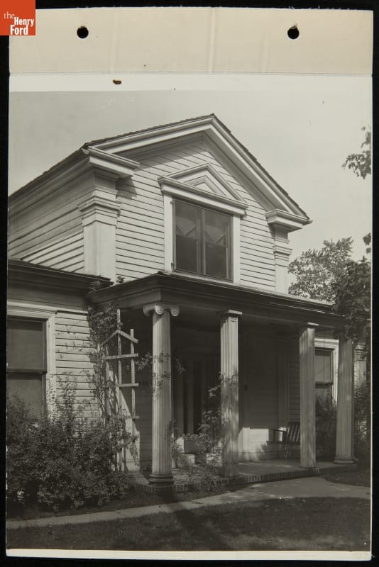 Front of two-story wooden house with porch with columns