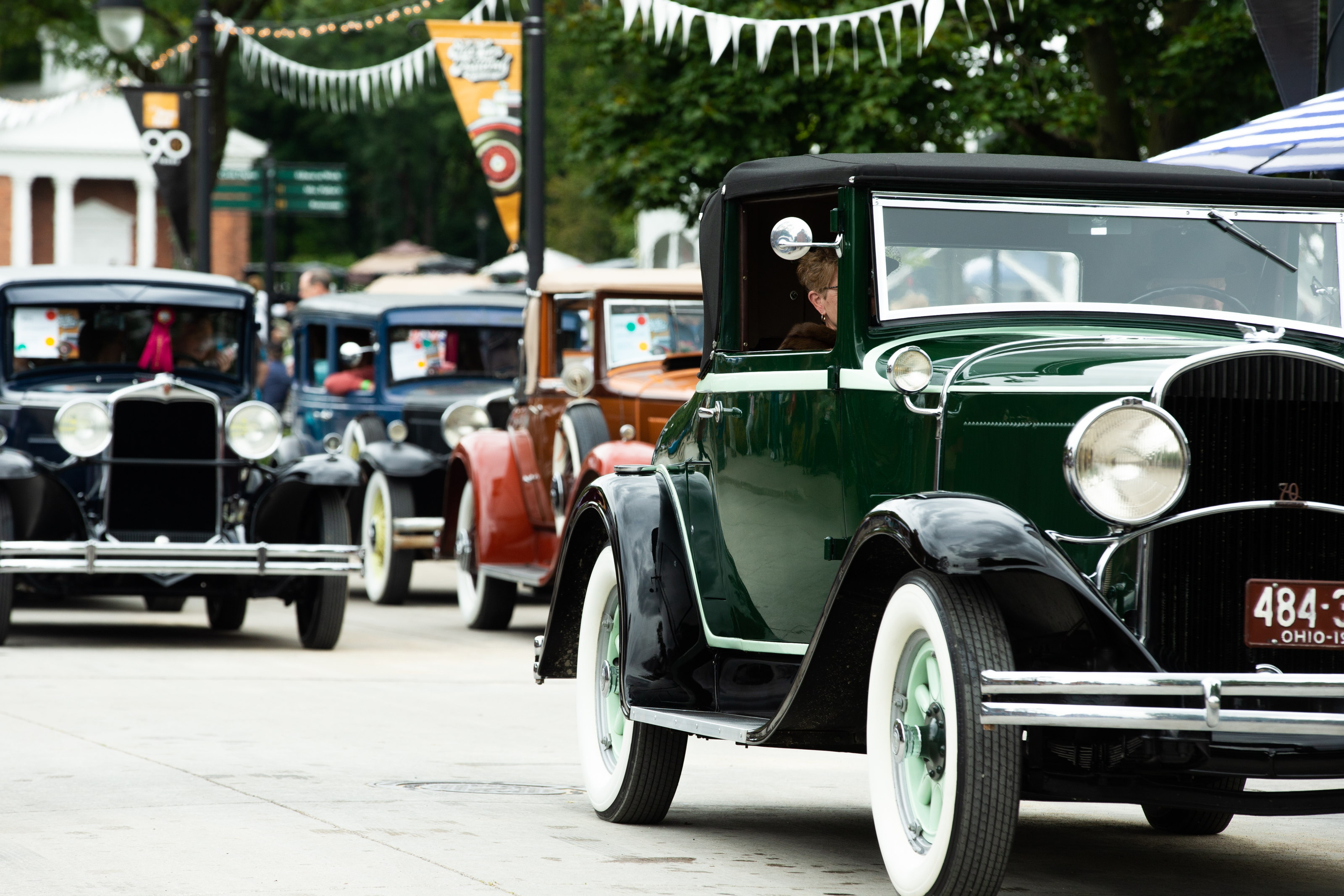 Cars driving through Greenfield Village Antique cars driving along concrete road