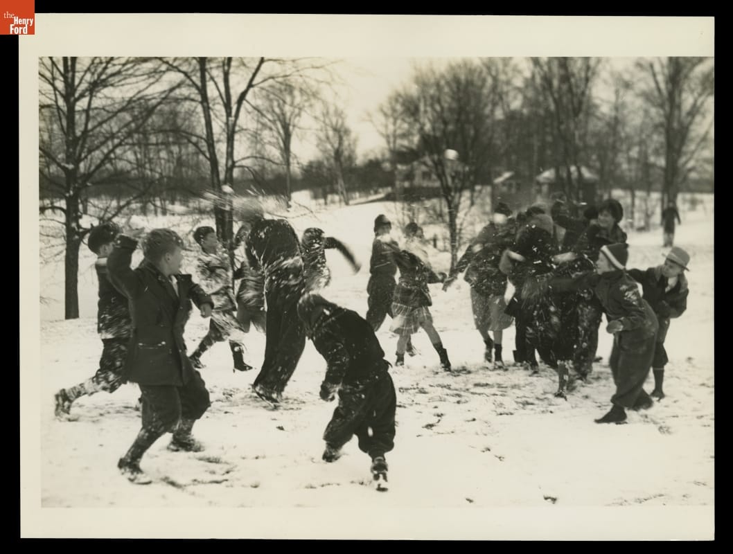 Group of children in a snowy field with trees throwing snowballs at each other