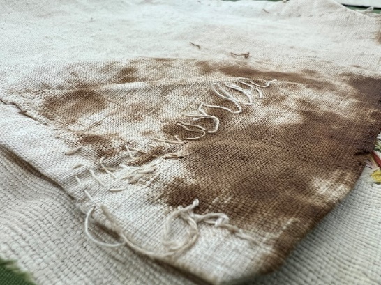 Beige fabric with dark brown staining and squiggly stitching