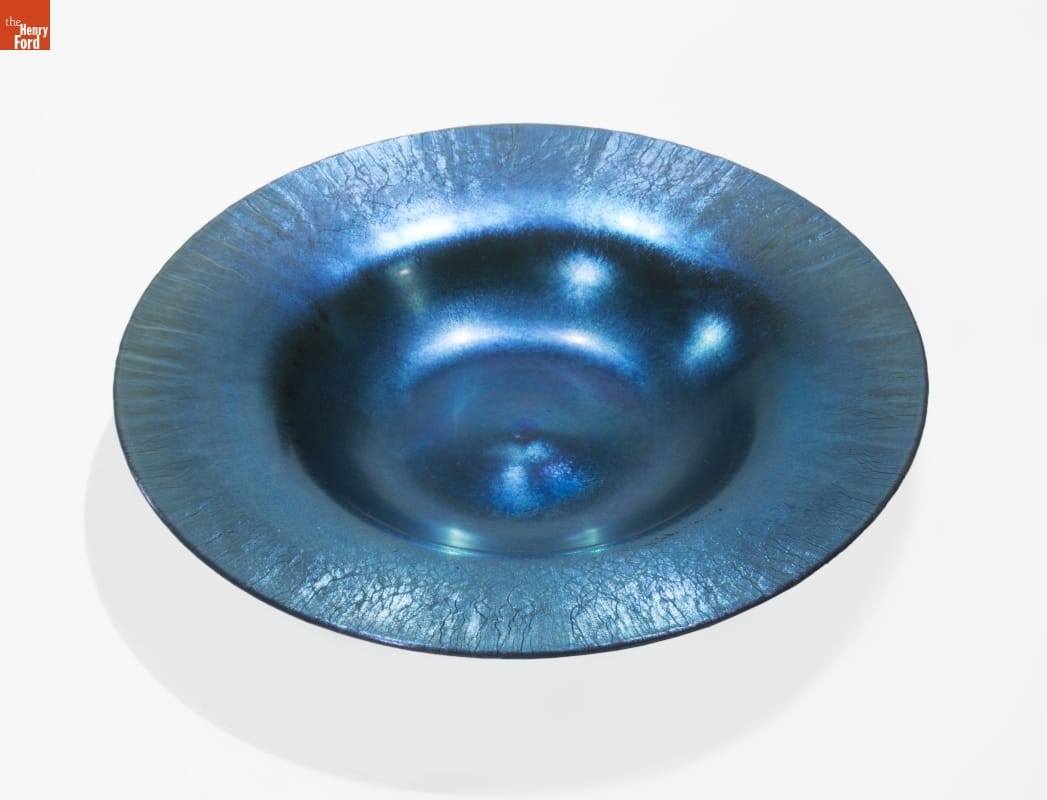 Dark blue iridescent dish with wide rim and shallow depression in center