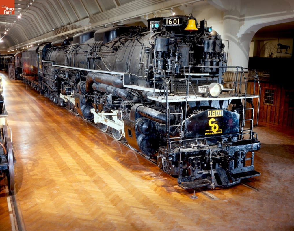 Large black locomotive in large room with wood floor and arched ceiling