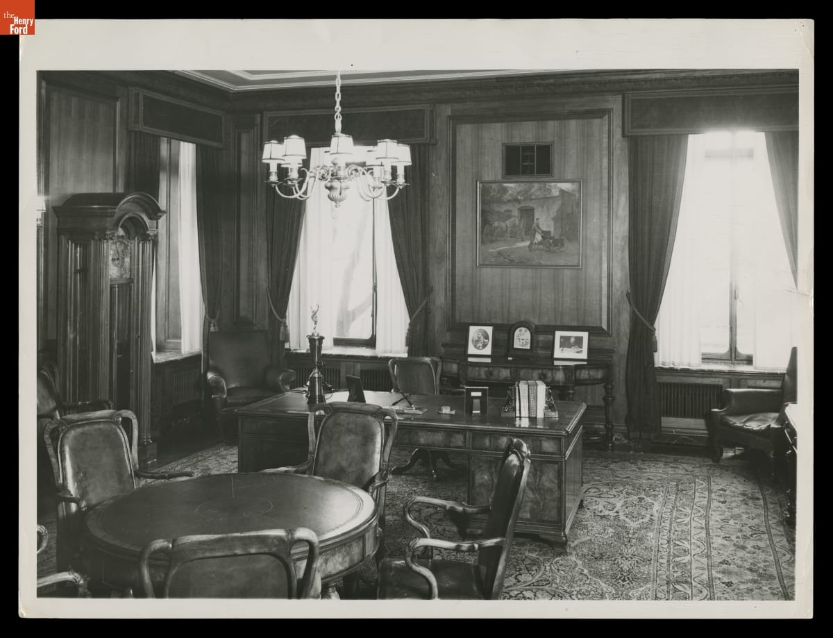 Interior of office with carpet, wooden furniture, and two windows behind desk