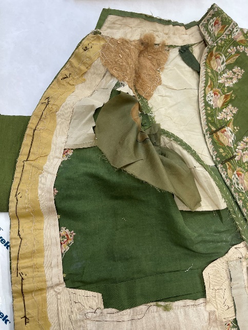 A coat interior lies flat on a table, revealing a patchwork of fabrics and stitching inside