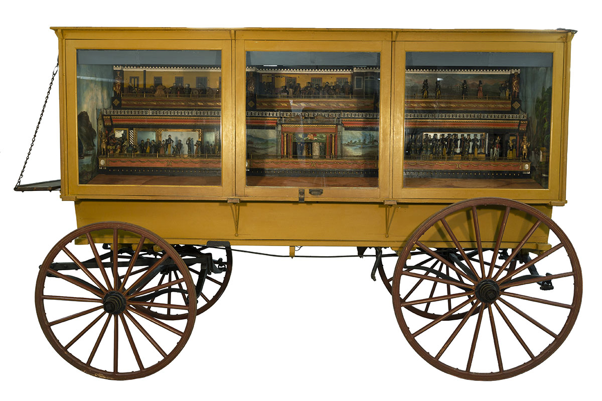 Mustard yellow wagon with three glass doors on side; miniature scenes visible inside doors