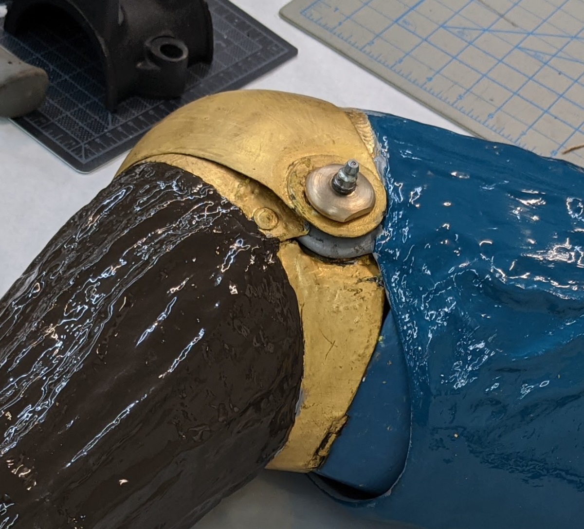 Painted and gold tubular shape with hinged bend in middle