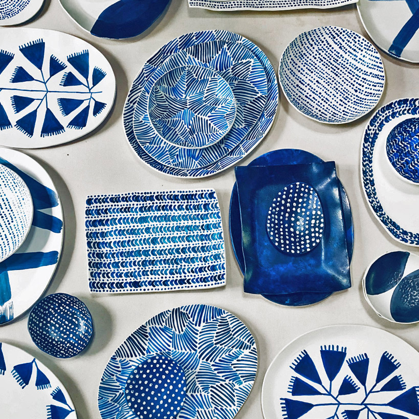 A variety of ceramic plates, bowls, and platters, all featuring white and blue painted patterns