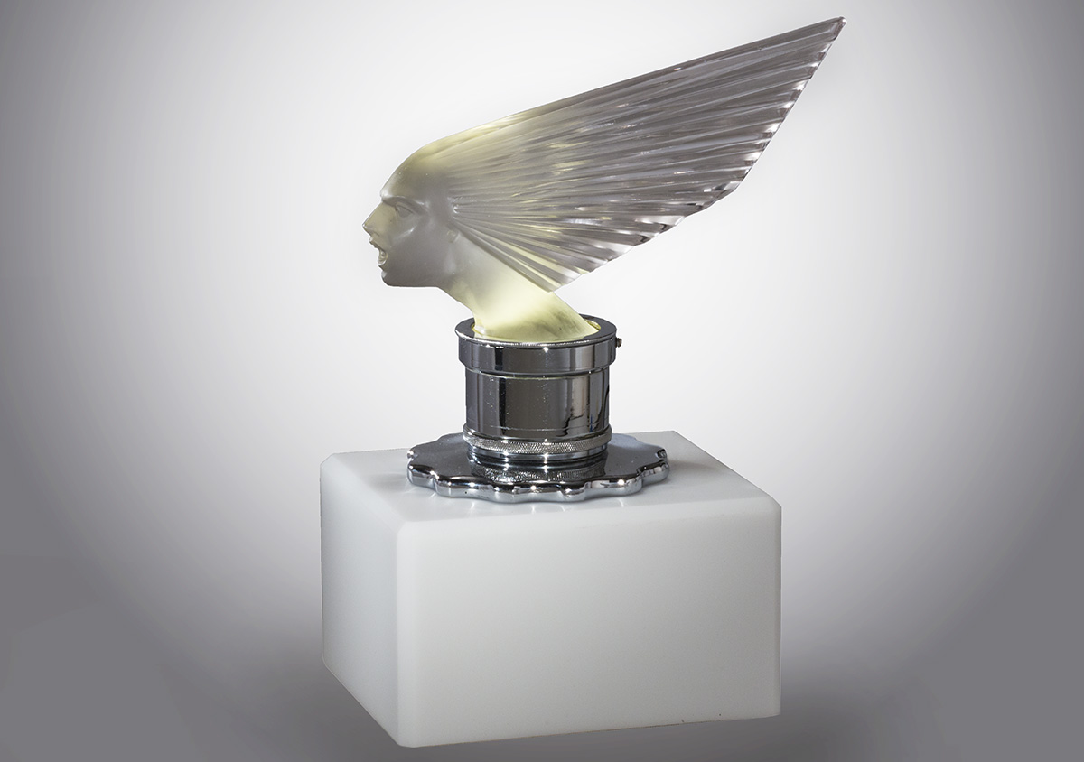 Lalique "Victoire" Hood Ornament, 1928-1930 Glass sculpture of face with hair stylized into a dramatic fan backwards, atop silver base/mount