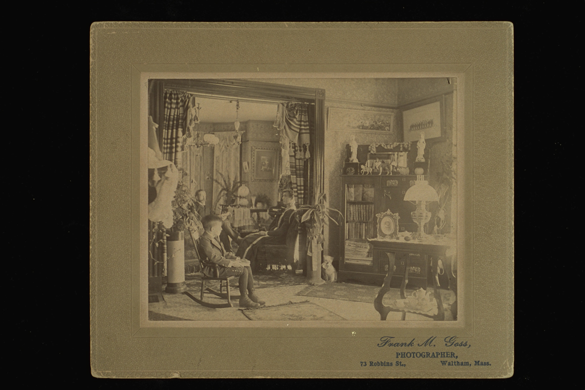 Family Parlor Portrait, circa 1900 Boy, woman, and man sitting in an extensively furnished room