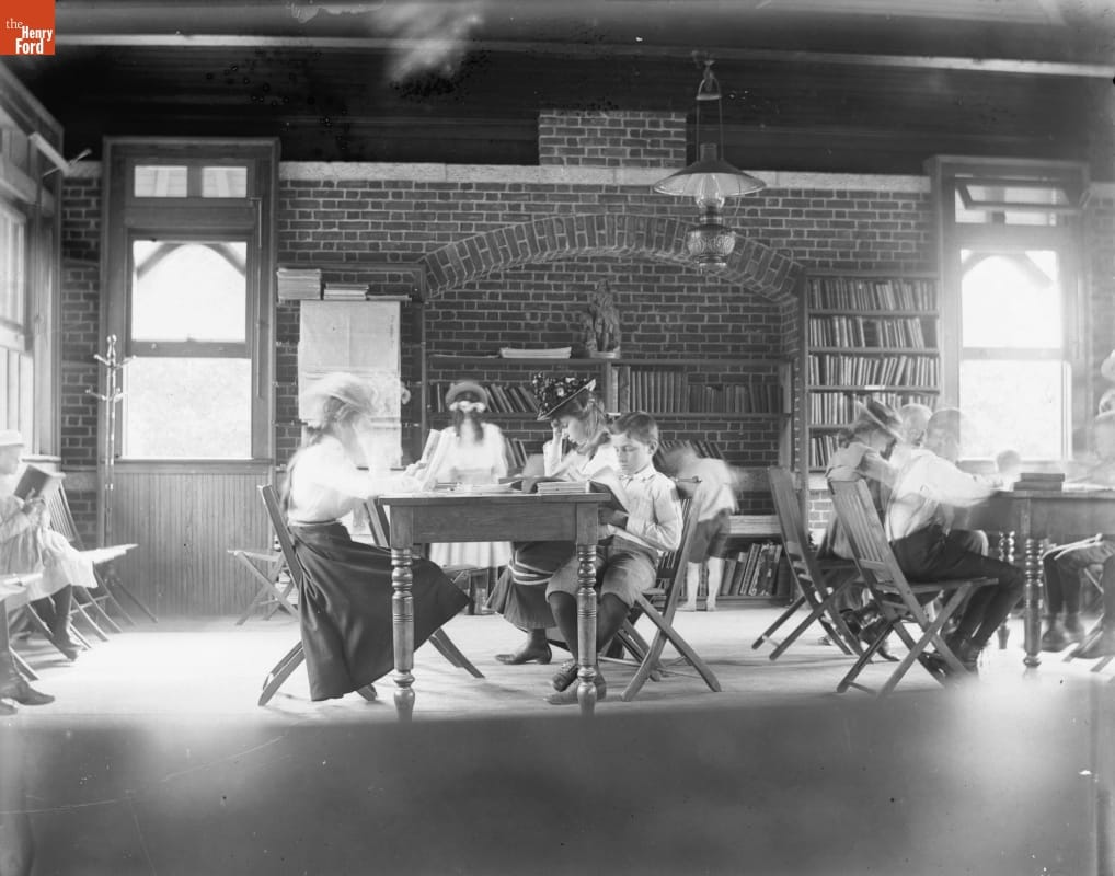 Photo taken by Jenny Young Chandler of young people sitting at tables and reading in the library in Tompkins Park, New York in 1910