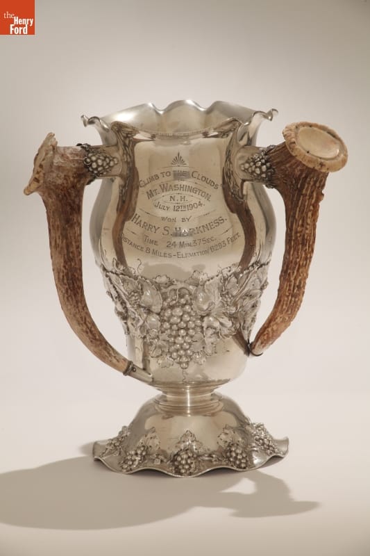 "Climb to the Clouds" Trophy Won by Harry S. Harkness, 1904 Silver vase-shaped trophy with text and pattern of grapes, and handles made out of antlers