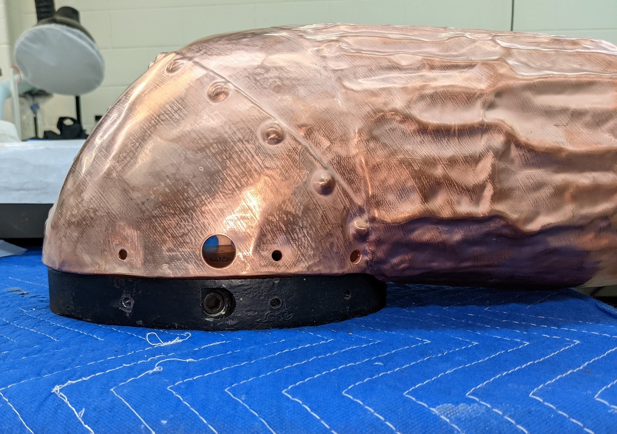 Copper form with black base sitting on blue quilted fabric