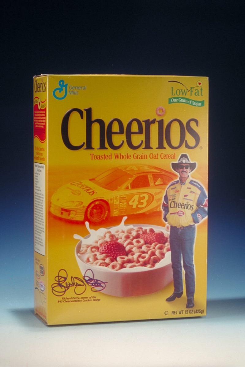 Yellow cereal box with images of a race car, bowl of cereal and milk, and a standing man; also contains text