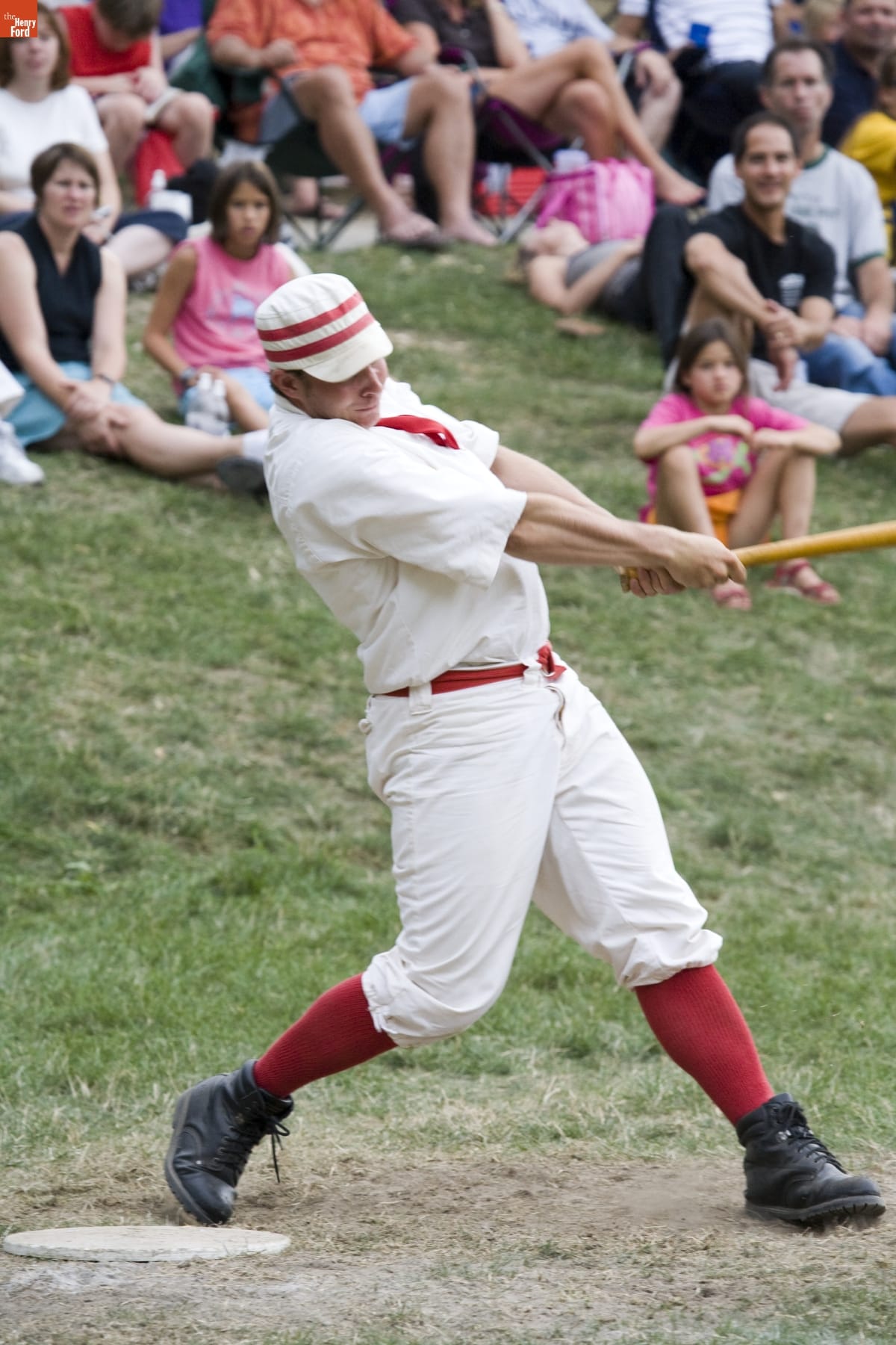 Man in baseball uniform swinging a bat, as crowds watch behind him