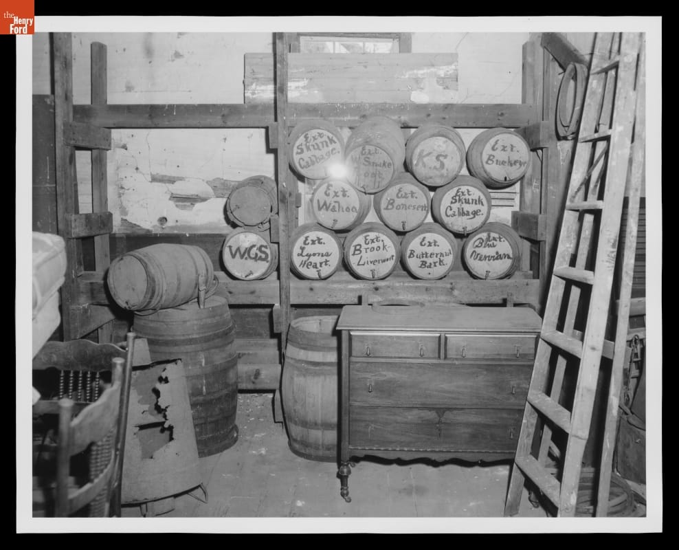Dusty room containing furniture and a number of casks or barrels on their sides with handwriting on the tops