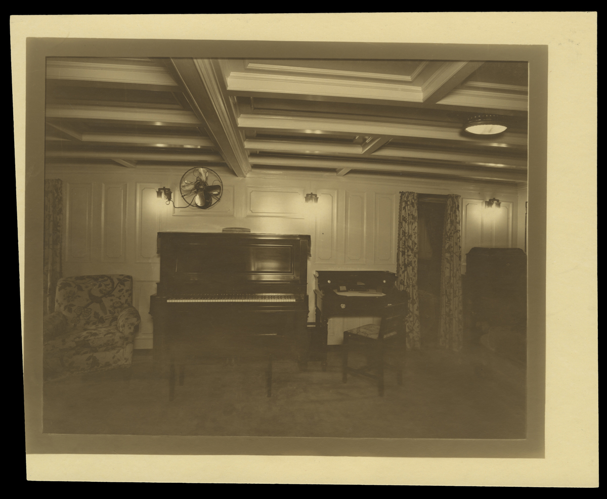 Room interior with piano, desk, upholstered chair