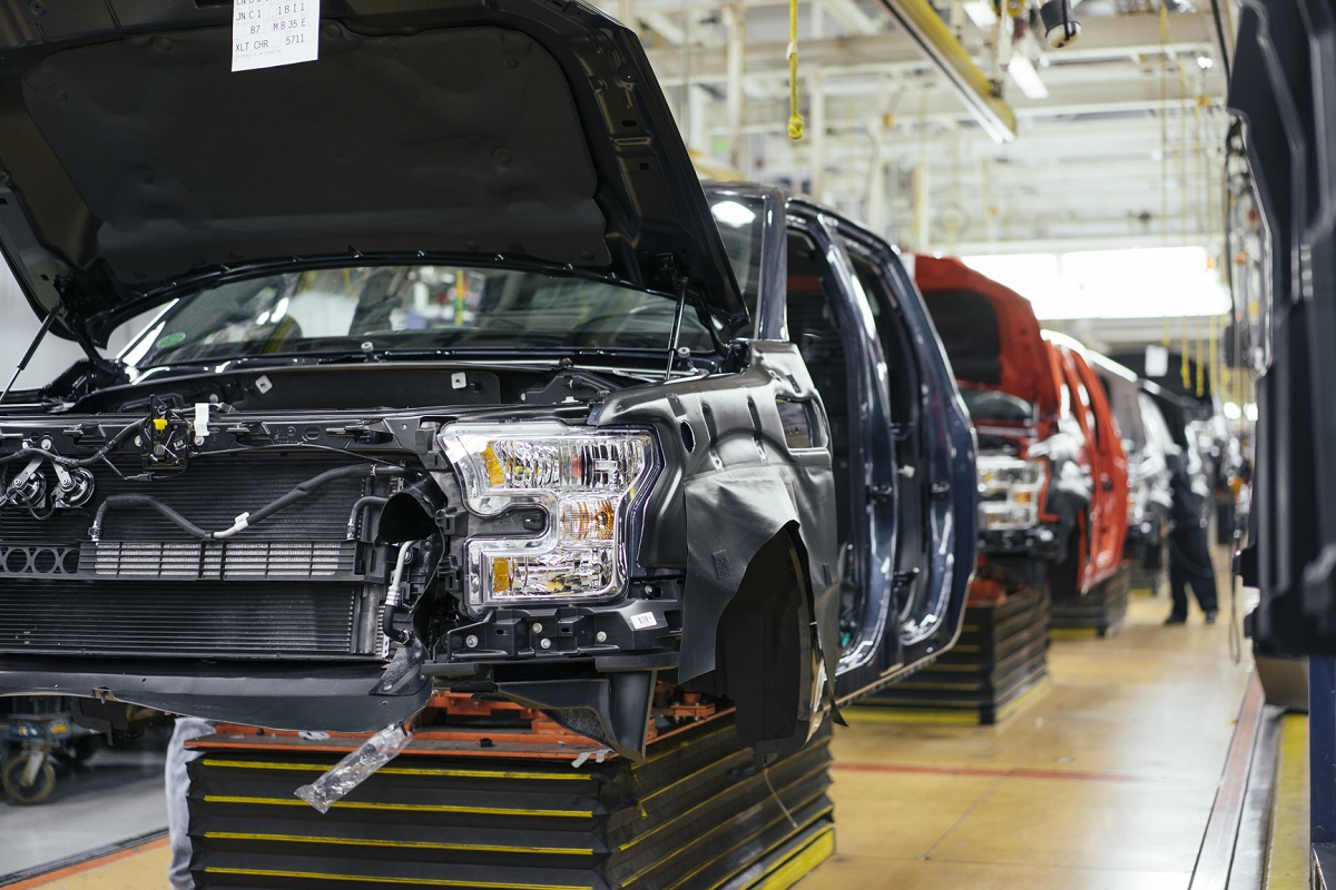 Partially assembled truck cabs on an assembly line; a person works on one in the distance