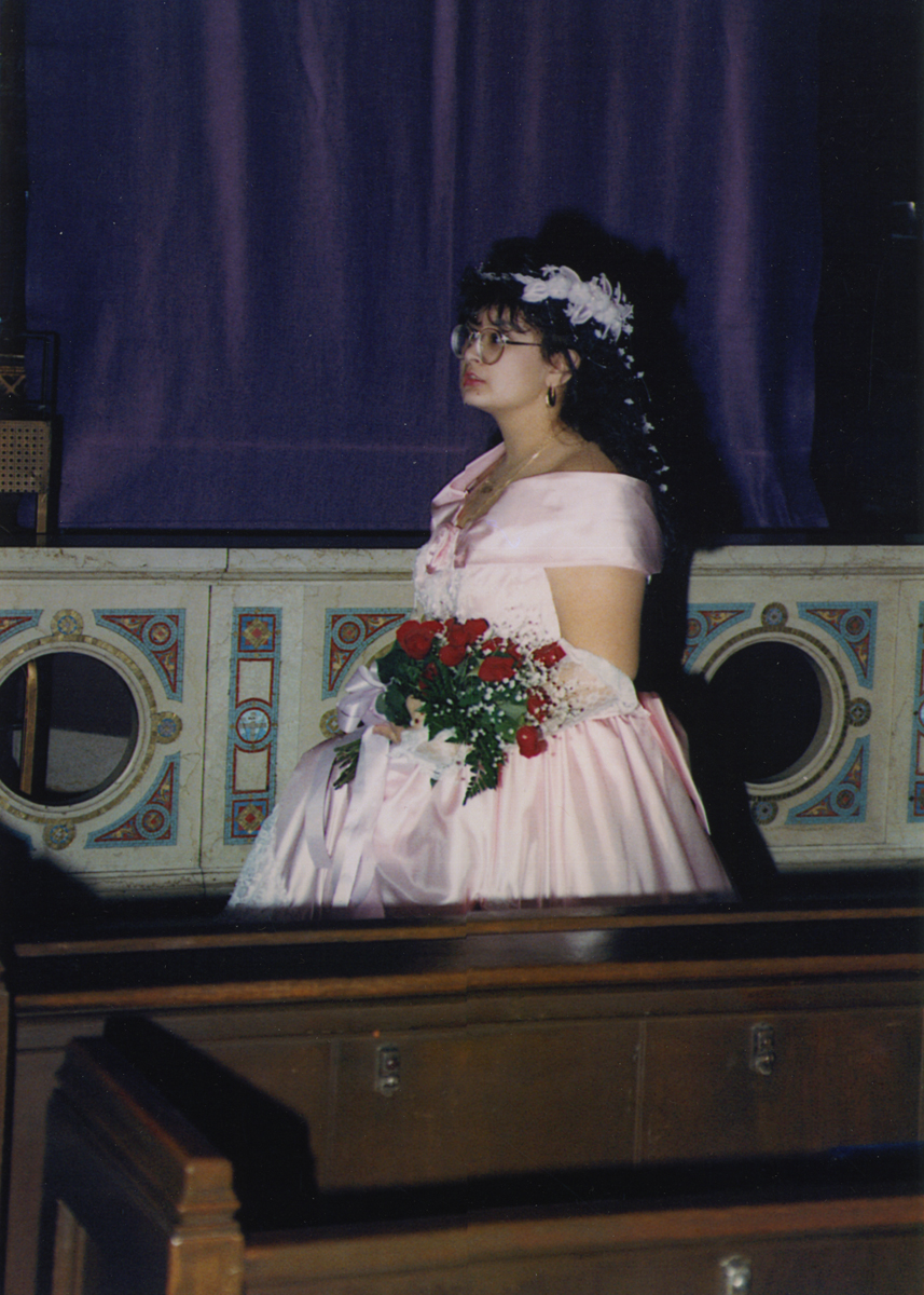 Maritza Garza at Her Quinceanera, Holy Redeemer Church, Detroit, Michigan, 1992 Profile of woman in pink dress holding a bouquet of roses in a formal building (church?)