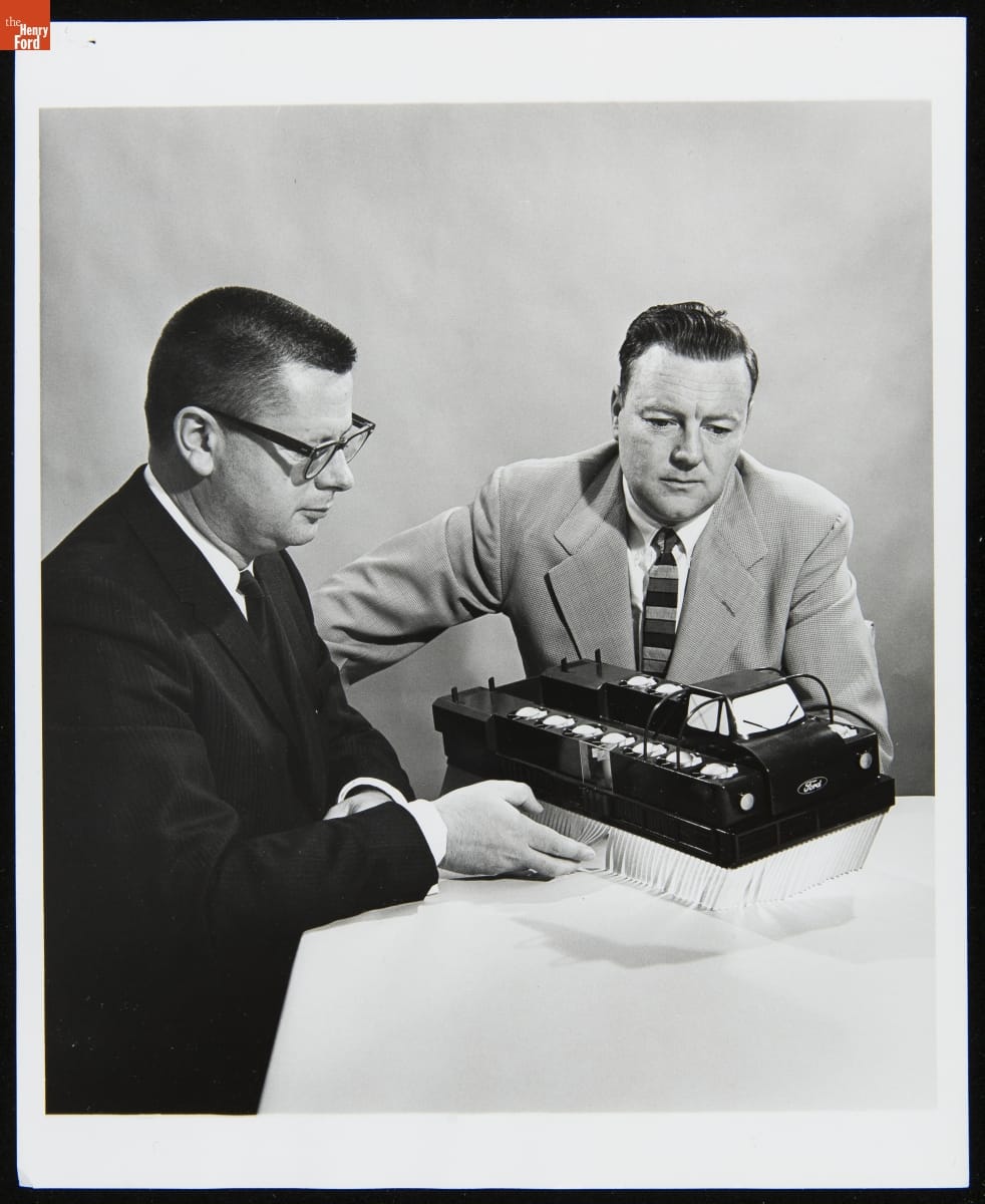 Project Engineers Study Air-Cushion Vehicle Scale Model, Aeronutronic Division of Ford Motor Company, March 1962 Two men in suits sit at a table, looking at a model of a truck-like vehicle with white fringe below body