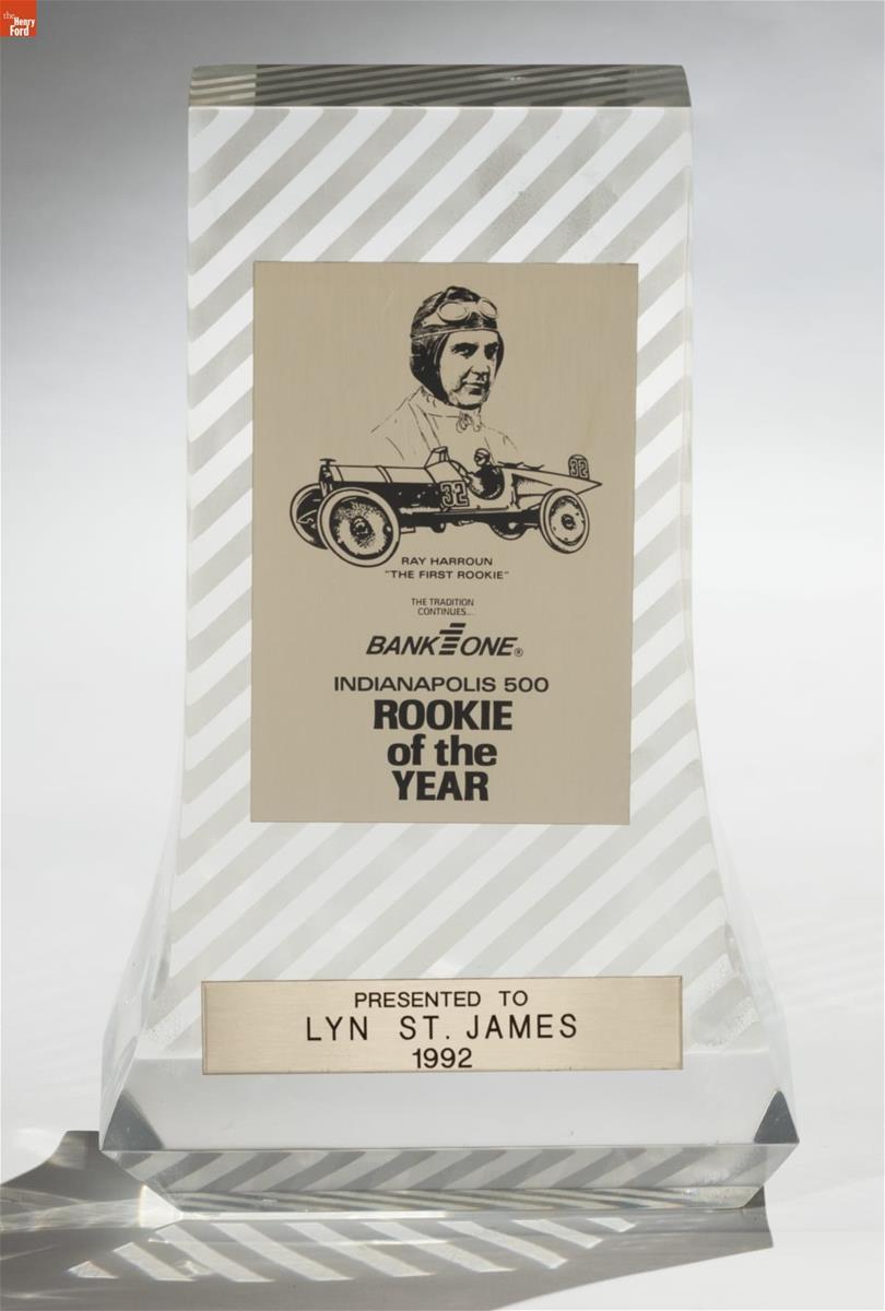 "Rookie of the Year" Trophy, Awarded to Lyn St. James at the 1992 Indianapolis 500 Clear glass or lucite trophy with diagonal stripes, and two panels with an image of a man in an old-fashioned racing helmet and goggles and an antique car, and text