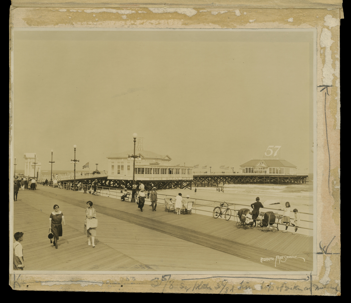 Black-and-white photo of people walking along a pier