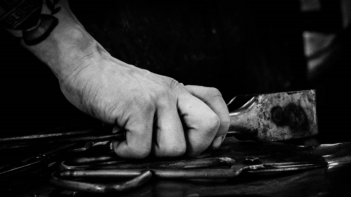 Black-and-white photo of hand clutching tool with other tools nearby