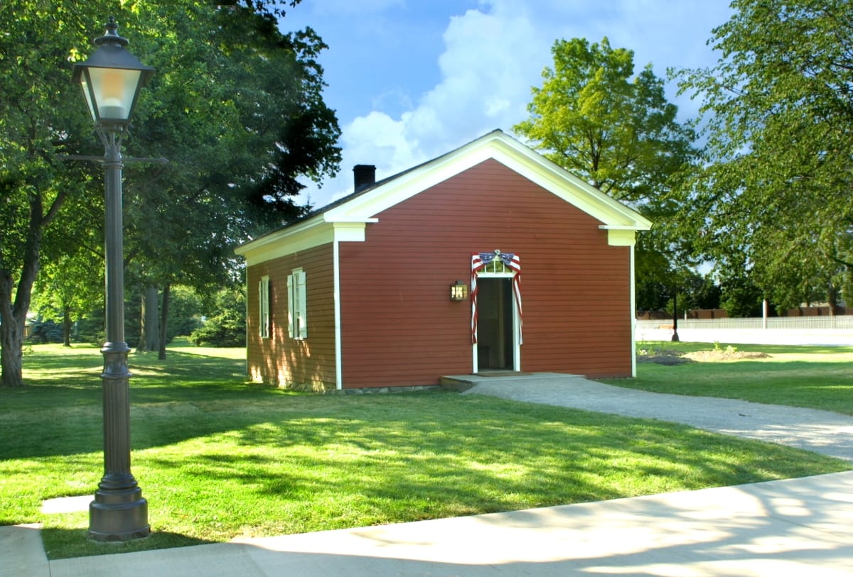 Dr. Howard's Office Small red wooden building among green lawns, trees, walkways, and streetlamps