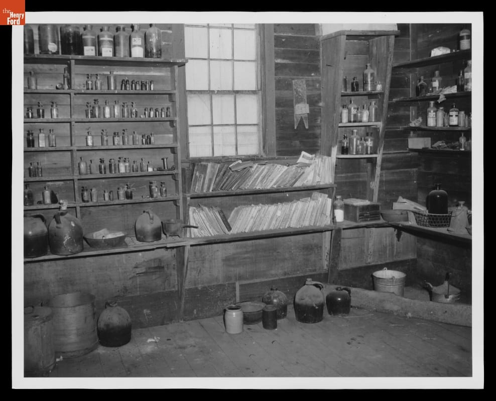 Room with one window and shelves covering almost all visible wall space, containing bottles, jars, papers, books